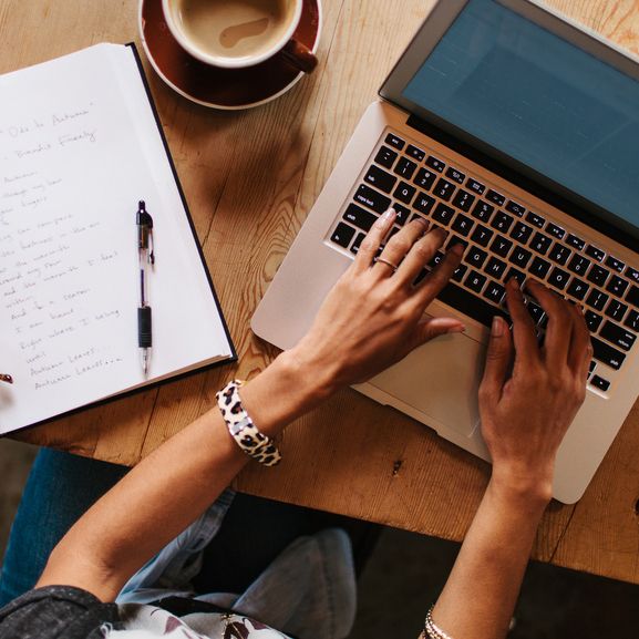 Woman Sitting At A Coffee Shop Table Working On A Laptop